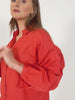 A video showing a model wearing the Martha shirt in red, turning for the camera to show the item from all angles and demonstrating the button on the cuff of the sleeve.   