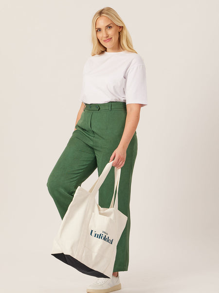 A model carries the Joey bag in their hand whilst wearing the white Penny t-shirt and olive Beth trousers, pictured against a white backdrop. 