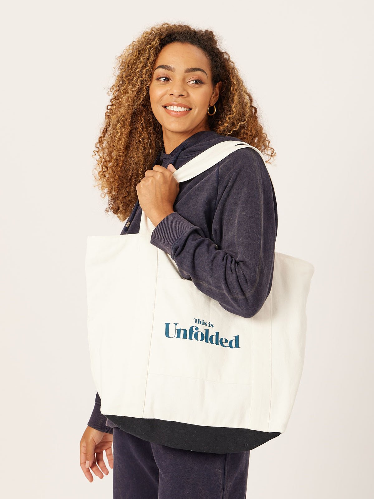 A model carries a Joey bag on their shoulder whilst wearing a coordinating set of Robyn joggers and a Willow hoodie, pictured against a white backdrop.