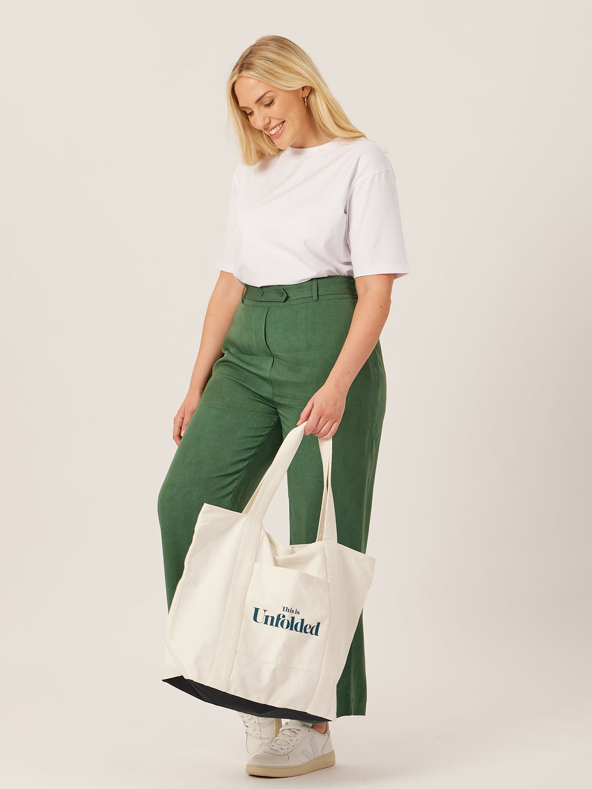 A model carries the Joey bag in their hand whilst wearing the white Penny t-shirt and olive Beth trousers, pictured against a white backdrop.