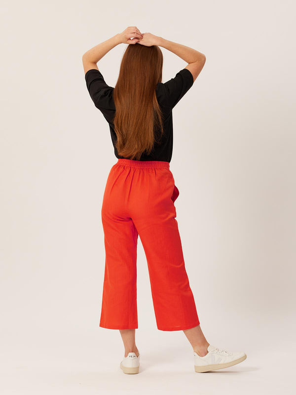 A model wears the Gigi trousers with the Penny t-shirt in black. They are pictured against a white backdrop from behind. 