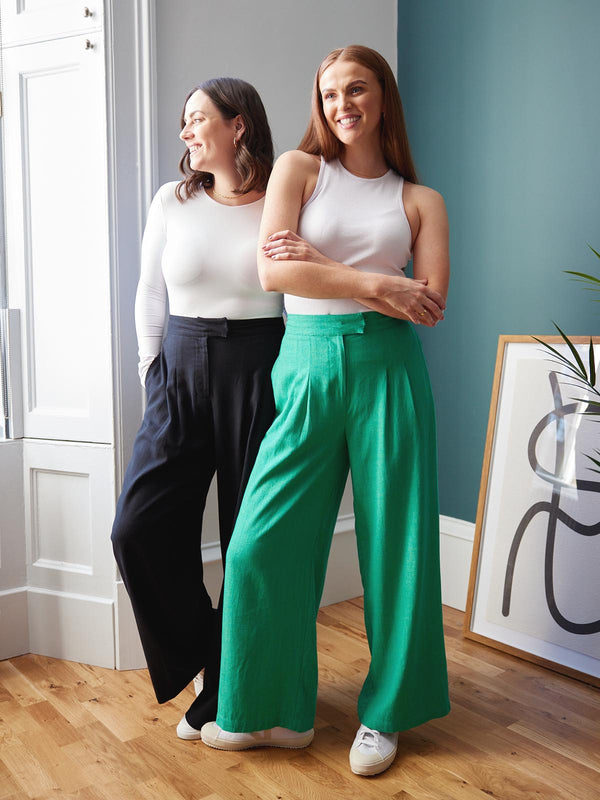 Two models, both wearing the Lana trousers - one in black and the other in green. Both models are smiling and looking in different directions.