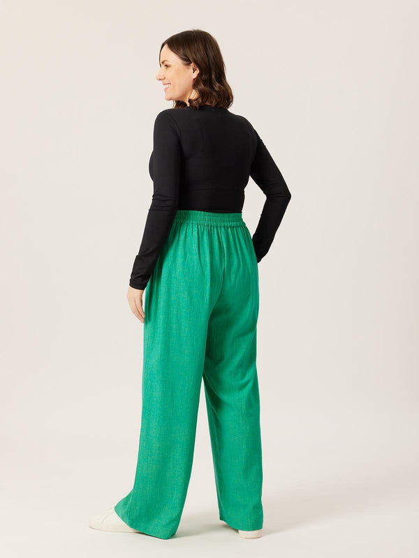A model wears the green Lana trousers with a long sleeve black t-shirt, pictured from the back and displaying the elasticated waist.