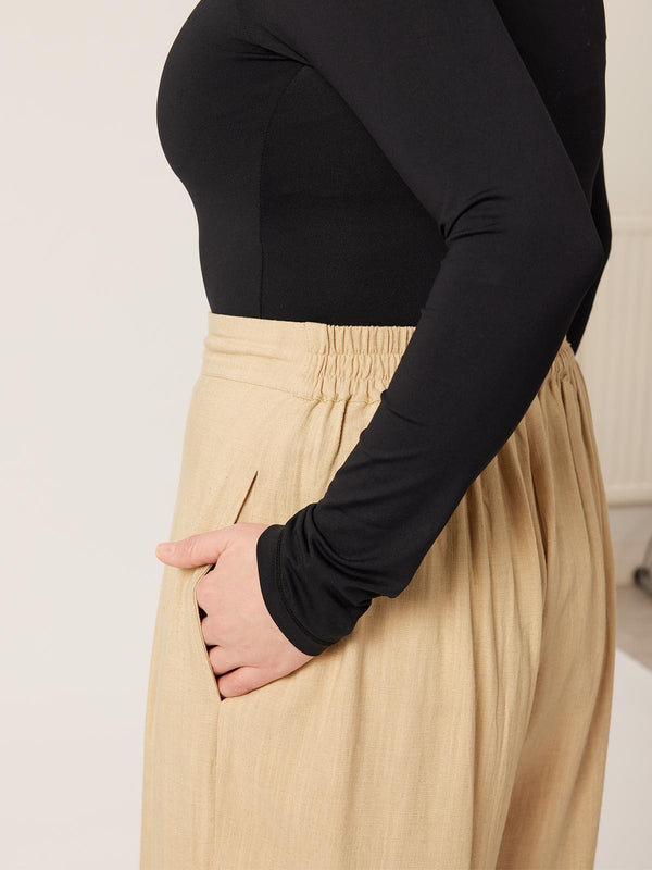 A close up of the side of a model wearing the Lana trousers in sand, with a focus on the pockets.