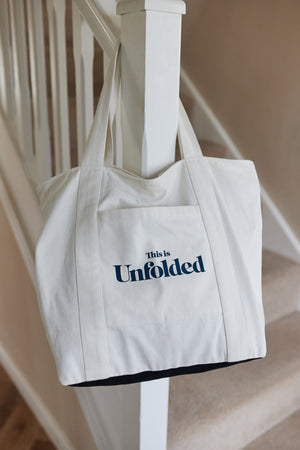 A Joey bag is pictured hanging on a bannister rail at the foot of a flight of stairs in a home. 