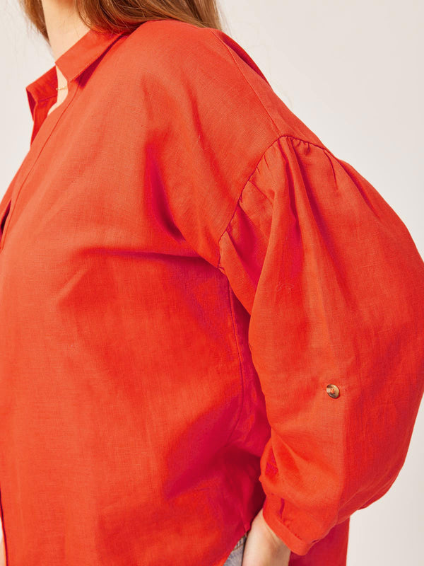 A close up of the Martha shirt in red, pictured worn by a model with a focus on the sleeve. 