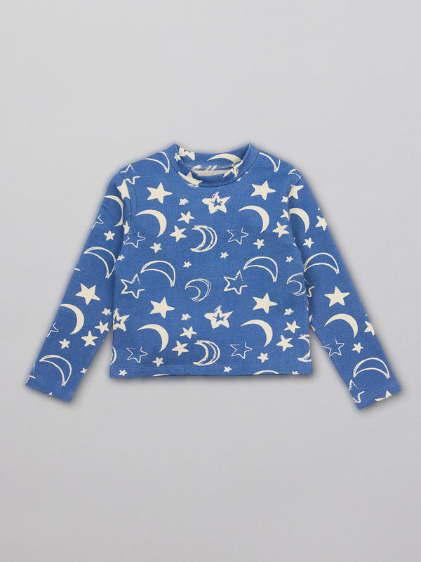 A sustainable kids pyjama top in blue with a white moon and star print, pictured from the front.