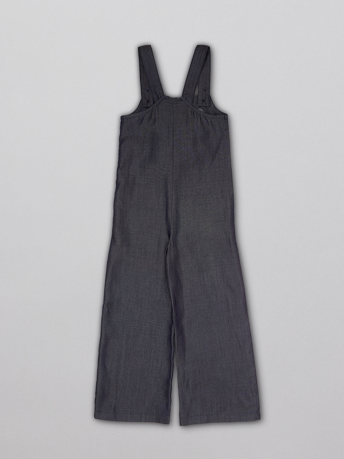 Sustainable dungarees for kids with a large front pocket and adjustable straps, pictured from the back.