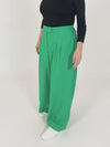 A video of a model wearing the green Lana trousers and a long sleeve black top. The focus is on the pockets, the elasticated waistband and the zip and clasp closure. 