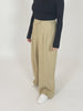 A video of a model wearing the Lana trousers in sand and a long sleeve black top. The model is turning around to display the trousers, and  is placing their hands in their pockets. 